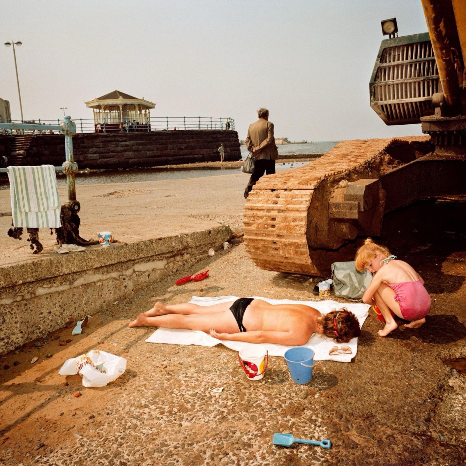 Uomo sdraiato, donna in spiaggia.